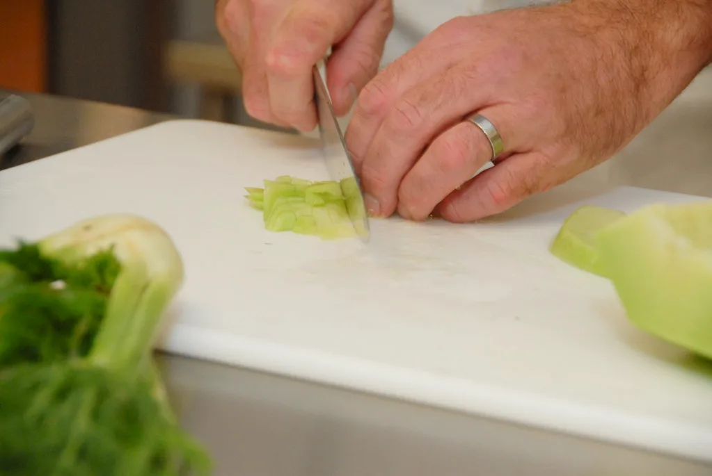 Manos de cocinero cortando verduras frescas